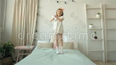 一个快乐可爱的小女孩，穿着白色连衣裙，在床上蹦蹦跳跳，微笑着的小孩子
